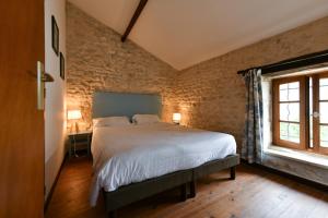 a bedroom with a bed and a brick wall at Domaine Les Granges in Saint-Jean-dʼAngély