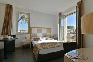 una camera d'albergo con un letto e una grande finestra di Hotel Le Chevalier a Taormina