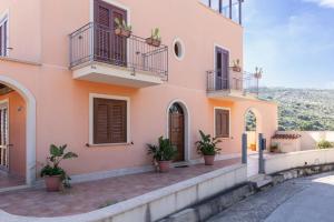 a pink house with potted plants in front of it at Appartamento Custonaci Uno in Custonaci