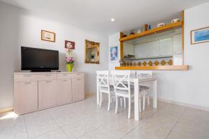 een woonkamer met een tafel en een televisie en een keuken bij Hauzify I Apartament Gavina in Salou
