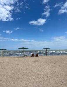 3 sillas y sombrillas en una playa con el océano en Goradil Beach en Bakú