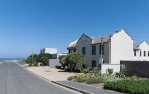 una casa blanca al lado de una calle en Blouberg Manor, en Bloubergstrand