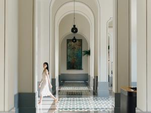 a woman walking down a hallway with a painting on the wall at Andaz Xiamen in Xiamen