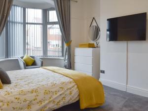 a bedroom with a bed with a yellow blanket on it at The Bungalow in Thornton