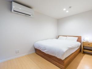 a white bedroom with a bed and a air conditioner at Rakuten STAY HOUSE x WILL STYLE Itoshima 105 in Itoshima