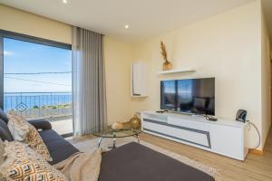 sala de estar con TV de pantalla plana grande en Canhas Residence I by Madeira Sun Travel, en Ponta do Sol