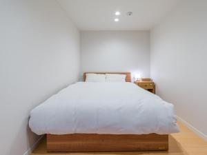 ein Schlafzimmer mit einem großen Bett mit weißer Bettwäsche in der Unterkunft Rakuten STAY HOUSE x WILL STYLE Itoshima 101 in Itoshima