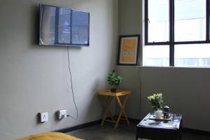 1 dormitorio con TV en la pared y mesa en Air: Fox on Maboneng, en Johannesburgo