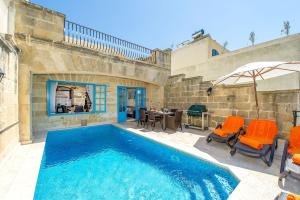 a swimming pool with orange chairs and a table at Ta Rena Holiday Home in Nadur