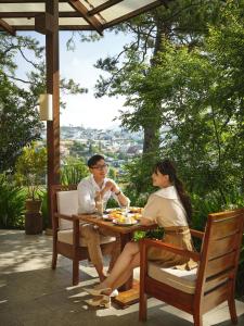 a man and woman sitting at a table on a patio at Ana Mandara Villas Dalat Resort & Spa in Da Lat