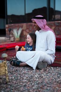 een man en een klein meisje zittend op de grond bij Milky Way Bedouin Camp in Wadi Rum