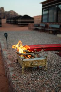 un feu dans une boîte assise au sol dans l'établissement Milky Way Bedouin Camp, à Wadi Rum