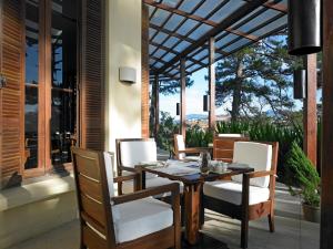a dining table and chairs on a porch with a view at Ana Mandara Villas Dalat Resort & Spa in Da Lat