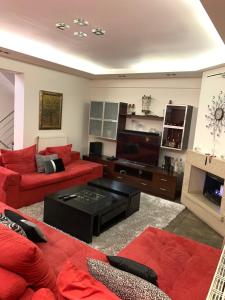 sala de estar con muebles de color rojo y TV de pantalla plana en Two Floor Luxurious Villa #skg, en Tesalónica