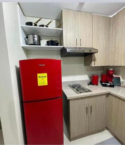 a red refrigerator in a kitchen with wooden cabinets at Twin lakes Merlot LL3-F in Tagaytay