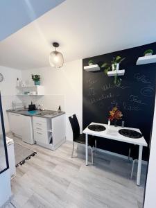 eine Küche mit einem weißen Tisch und einer schwarzen Wand in der Unterkunft Tramini Apartmanok in Eger