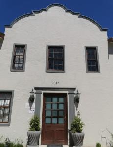 a white building with a brown door and windows at Blouberg Manor in Bloubergstrand
