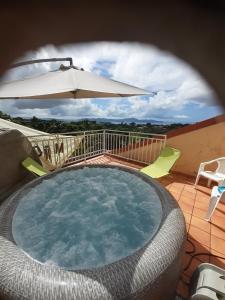 una piscina con sombrilla, mesa y sillas en JOYAUX DE TIVOLI VILLA en Fort-de-France