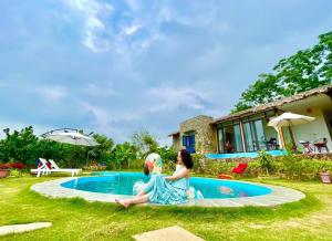 ハノイにあるNature’s House Ba Vi - Venue Travelの二人の女性がスイミングプールの隣に座っている
