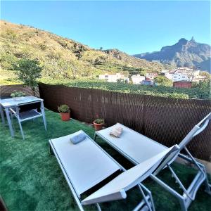 特赫達的住宿－Casa Maruca with Roque Nublo view，院子里设有两把椅子、一张桌子和一张桌子及椅子