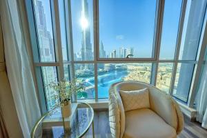 um quarto com uma cadeira e uma mesa de vidro em frente a uma janela em Magnificent Luxury 3BR with Amazing Burj & Fountain view em Dubai