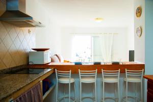 a kitchen with a counter with four bar stools at La Concha Beach apartament in Arrecife