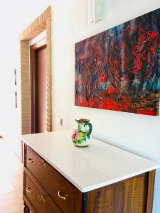 a vase sitting on a counter in a room with a painting at Residenza Locci - Rooms & Apartments in Teulada