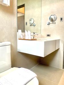 uma casa de banho com um lavatório branco e um espelho. em The Henry Hotel Roost Bacolod em Bacolod