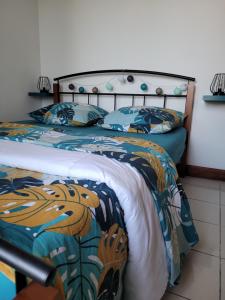 um quarto com uma cama com um cobertor e almofadas em Escale 86 em Sainte-Marie