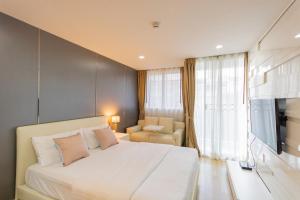 a bedroom with a bed and a couch and a television at United Residence Ekamai Bangkok in Bangkok