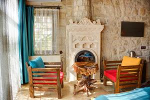 a living room with a fireplace and two chairs at Efendi Cave Hotel in Urgup