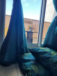 einem Sitz vor einem Fenster mit blauen Vorhängen in der Unterkunft Escale 86 in Sainte-Marie