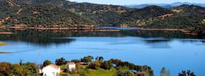 a large lake with a house in the middle at Finca La Vicacaria LIMONERO in Zufre