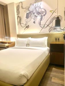 1 dormitorio con 1 cama con una pintura en la pared en The Henry Hotel Roost Bacolod en Bacólod