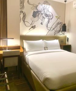 um quarto com uma cama e um quadro na parede em The Henry Hotel Roost Bacolod em Bacolod