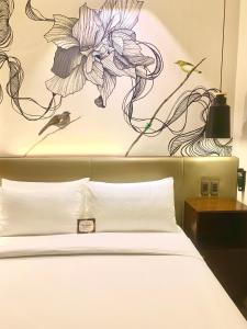 1 dormitorio con 1 cama con una pintura floral en la pared en The Henry Hotel Roost Bacolod en Bacólod