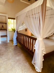 - une chambre avec un lit à baldaquin et des rideaux blancs dans l'établissement Cafe Ceylon, à Koggala