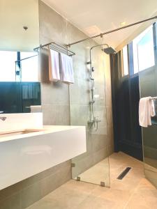 a bathroom with a shower and a sink and a mirror at The Henry Hotel Roost Bacolod in Bacolod