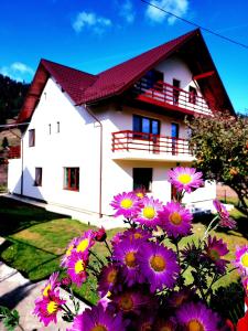 a white house with purple flowers in front of it at Casa Elena in Ceahlău