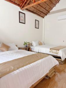 Habitación con 2 camas, paredes blancas y suelo de madera. en Chu Thuong Bungalow, en Ninh Binh