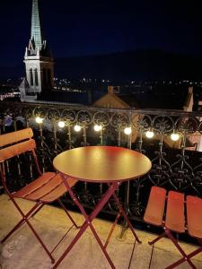 una mesa y sillas en un balcón por la noche en Studio cosy, hyper centre d'Aix, vue montagnes, proche thermes, en Aix-les-Bains
