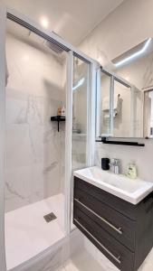 a white bathroom with a sink and a shower at Appart spacieux et lumineux à 5 min de la gare in Troyes