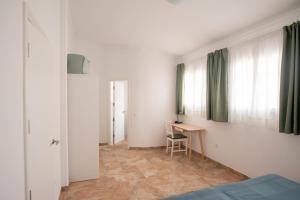 een kamer met een bed, een bureau en ramen bij Wohnung Buganvilla in Agüimes