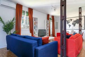 a living room with blue and red furniture and a tv at Confortable piso 3 habitaciones en Retiro Atocha in Madrid