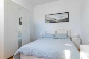 a white bedroom with a bed and a picture on the wall at Confortable piso 3 habitaciones en Retiro Atocha in Madrid
