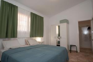 sypialnia z niebieskim łóżkiem i zielonymi zasłonami w obiekcie Cardón w mieście Agüimes