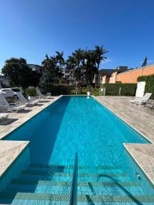 uma piscina com água azul e espreguiçadeiras em Arco do Sol Park Hotel em Camboriú