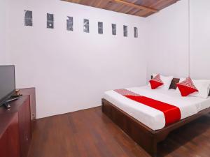a bedroom with a bed and a flat screen tv at OYO 91807 Kemalasari Guesthouse in Jambi