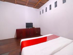 a bedroom with a red and white bed and a tv at OYO 91807 Kemalasari Guesthouse in Jambi