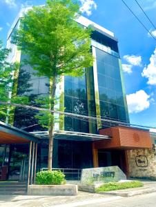 un edificio con un árbol delante de él en The Henry Hotel Roost Bacolod, en Bacolod